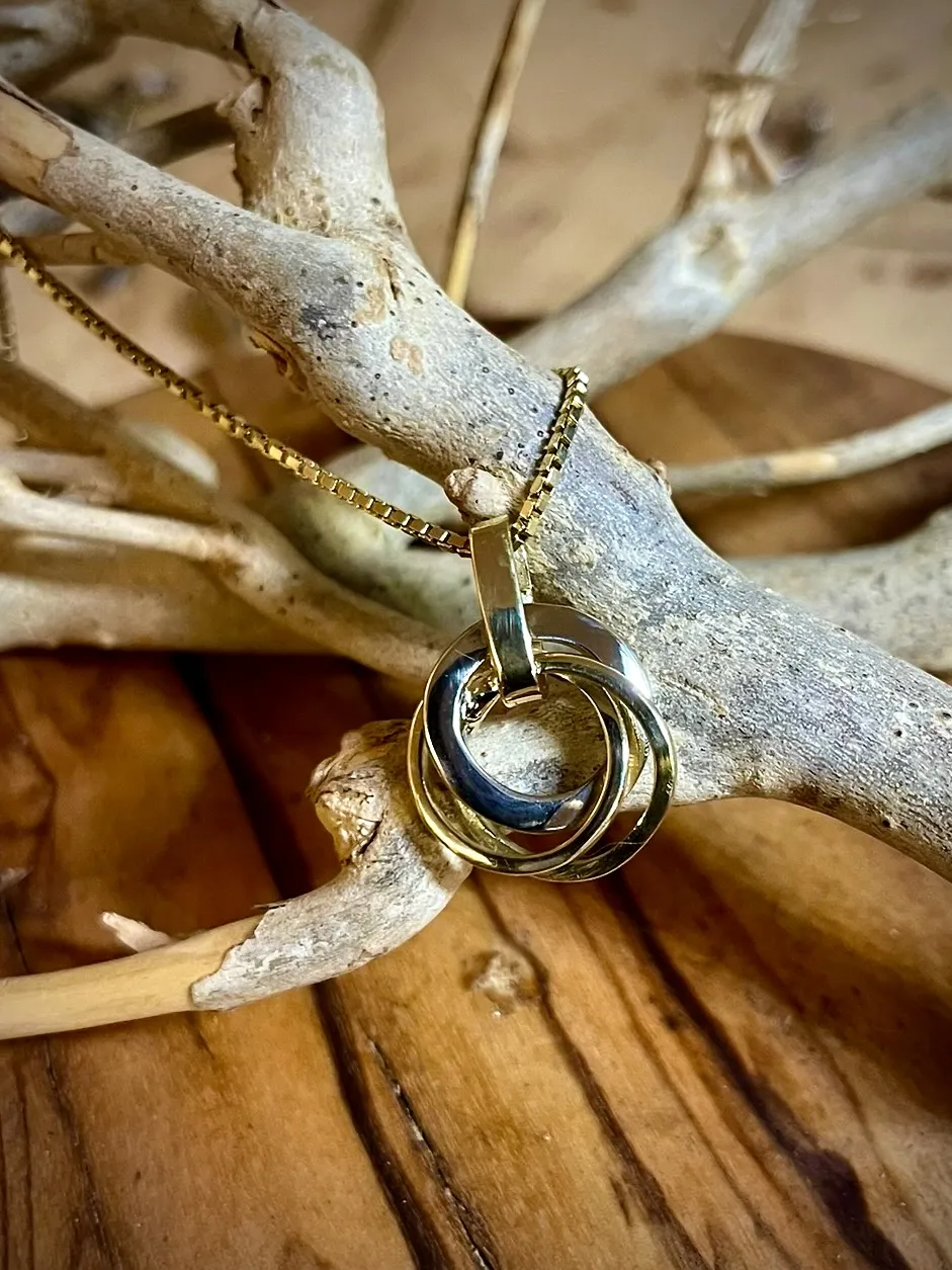 Gouden en witgouden hanger van ineengrijpende ringen aan gouden ketting